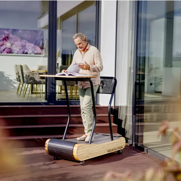 Man benutzt Laufband mit Schreibtisch zum Lesen auf Terrasse Walkolution Germany